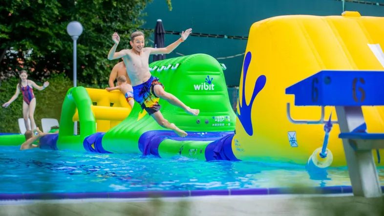 Junge springt freudig ins Freibad des Aquafun Soest an einem sonnigen Tag.