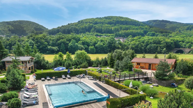 Fernblick auf den Außenpool des Aquamagis Plettenberg, umgeben von grüner Landschaft.