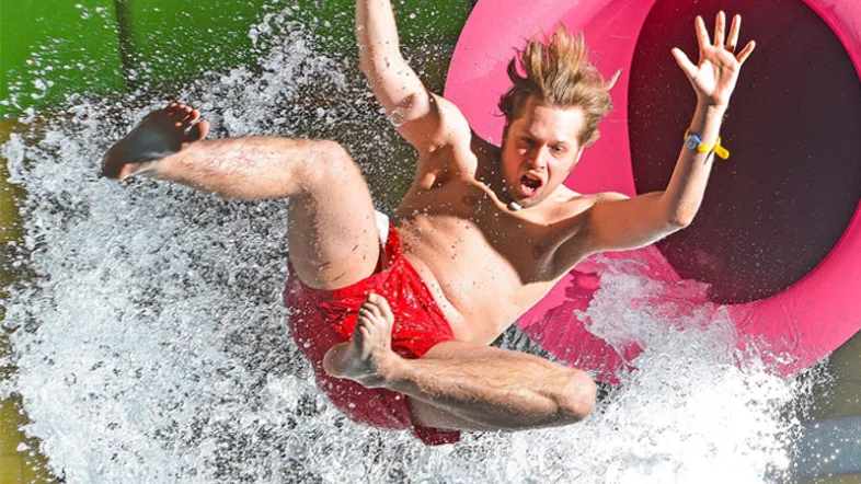 Mann rutscht mit Schwung die Wasserrutsche im Aquamagis Plettenberg hinunter.