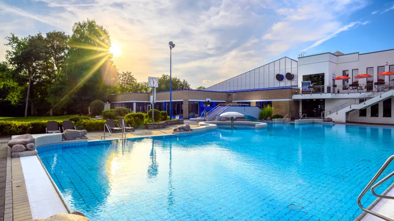 Außenpool des Aquarius Borken bei Sonnenschein mit glitzerndem Wasser und Liegeflächen.