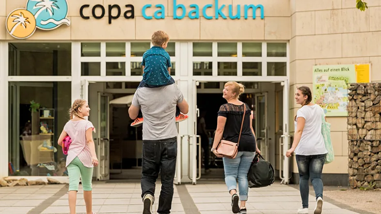 Familie betritt gemeinsam den Eingangsbereich des Copacabackum Herten an einem sonnigen Tag.
