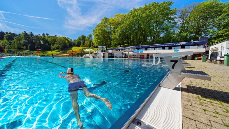 Schwimmer im Freibad Witten Annen ziehen ihre Bahnen im klaren Wasser.