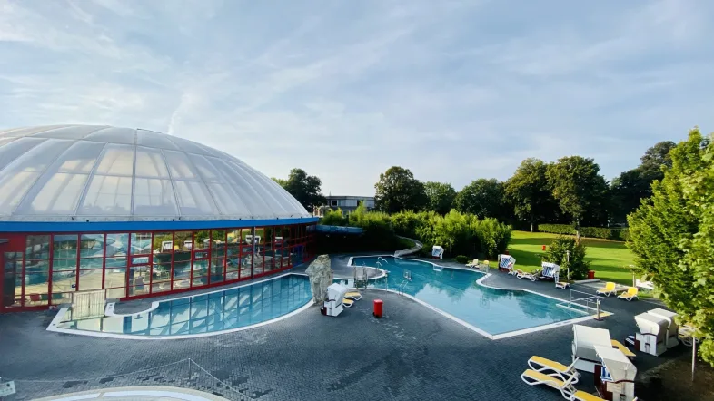 Außenbereich des Atlantis Dorsten mit Sonnenterrasse, Liegestühlen und grünem Garten.