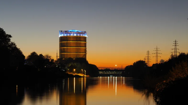Gasometer Oberhausen in Außenansicht bei Sonnenuntergang mit warmem Abendlicht.