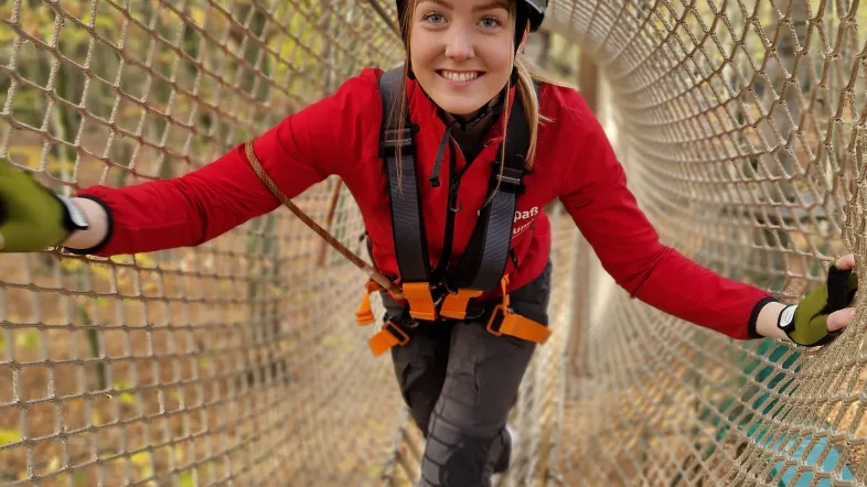 Eine Frau klettert durch einen Tunnel aus Seilen im Kletterwald Freischütz.