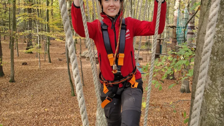 Frau hält sich an zwei Seilen fest im Kletterwald Freischütz.