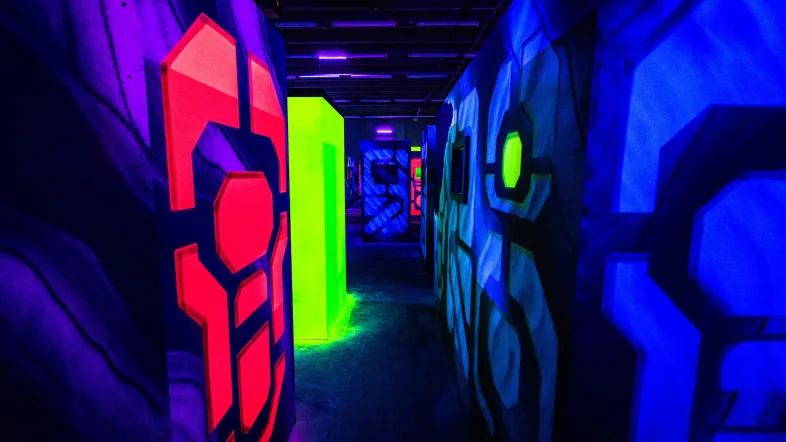 Enger Durchgang mit Hindernissen in der Laserzone Essen, beleuchtet mit Neonlicht.