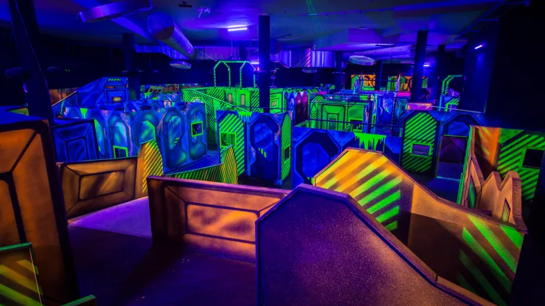 Panoramablick auf die Spielfläche der Laserzone Essen mit Neonlichtern und Hindernissen.