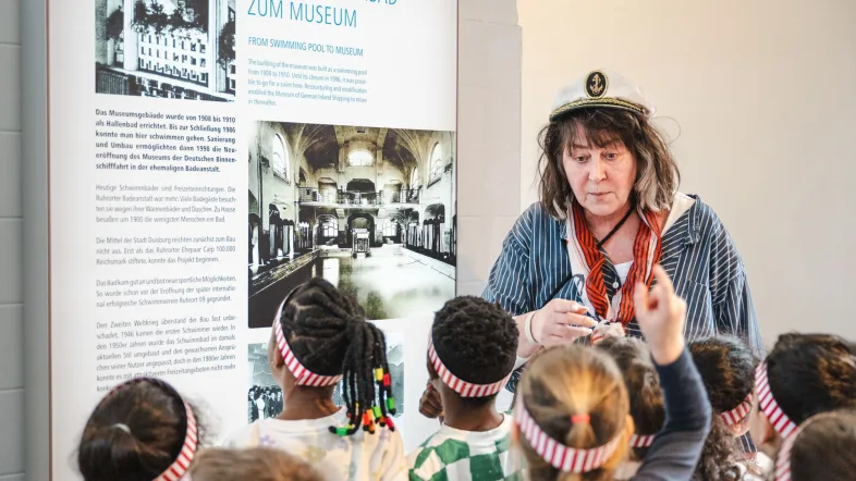Frau erklärt einigen Kindern innerhalb einer Führung etwas im Museum der deutschen Binnenschifffahrt in Duisburg.