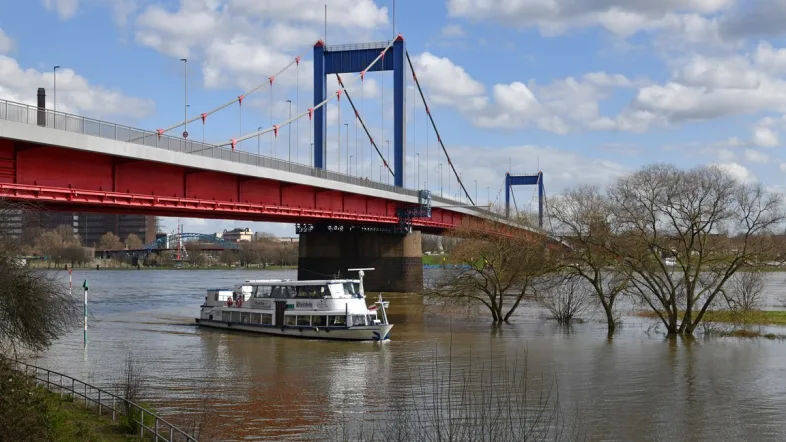 ersonenschiff der Ruhrorter Schifffahrt fährt unter einer Brücke hindurch, umgeben von urbaner Kulisse.