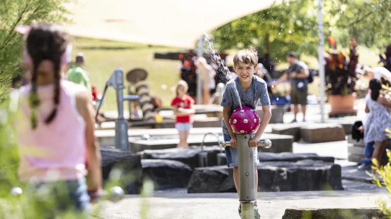 Kinder spielen an einem sprudelnden Wasserspielplatz im Sauerlandpark Hemer bei sonnigem Wetter.
